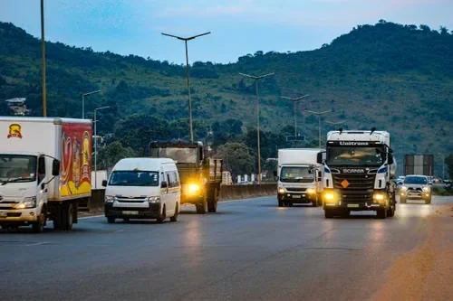 Haulage trucks, vans and a delivery truck on an East African highway at dusk