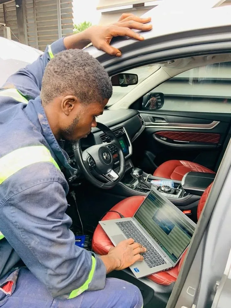 Installer fitting a tracker with a laptop open on the passenger seat