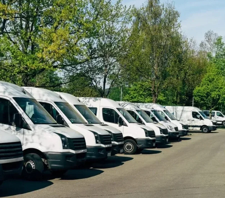 Row of white delivery vans parked in a depot yard